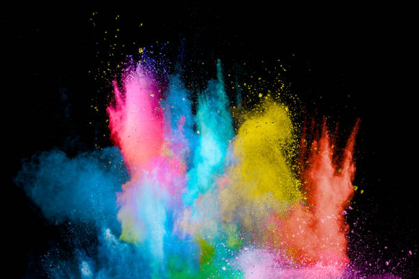 Explosion of colorful Holi powder on black background. Vibrant color dust particles textured background. Explosion of colorful Holi powder on black background. Vibrant color dust particles textured background. holi photos stock pictures, royalty-free photos & images