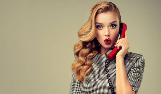 Expression of shock and excitement on the face of young woman.Blonde in shock. Expression of shock, excitement and amazement on face of perfectly looked, young, beautiful woman with old fashioned, red phone in her hand.. Extremely surprised facial expression. Pin-up style make up, hairstyle and red manicure. vintage beauty salon stock pictures, royalty-free photos & images