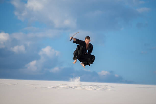 Expressive man jumps with a Japanese sword, katana stock photo