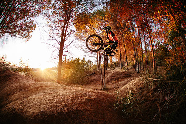 Exteme mountain biker performing aerial maneuvers while dirt jum Exteme mountain biker dirt jumping and performing aerial maneuvers on a forest track mountain bike stock pictures, royalty-free photos & images