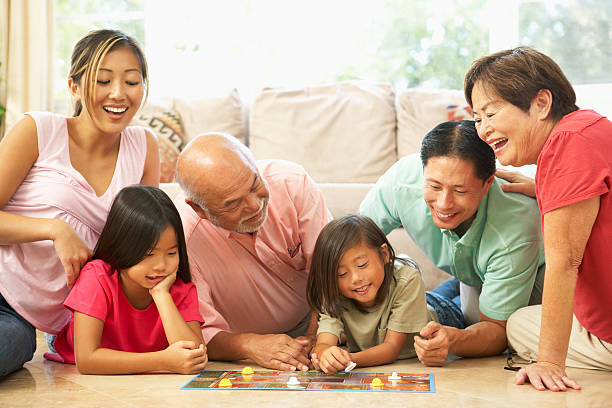 Extended Family Group Playing Board Game At Home Extended Family Group Playing Board Game In Living Room At Home board game photos stock pictures, royalty-free photos & images