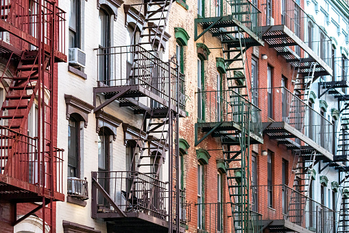 Exterior view of old apartment buildings with fire escapes on 6th Street in the East Village neighborhood of New York City NYC
