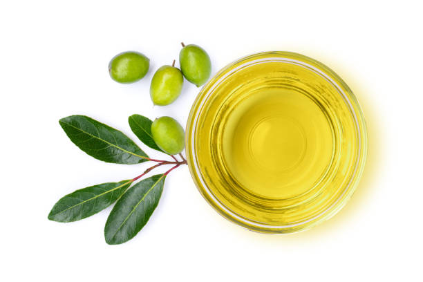 Extra virgin olive oil on white Extra virgin olive oil in glass bowl and green olive fruit with leaves isolated on white background. Top view. Flat lay. green olives jar stock pictures, royalty-free photos & images