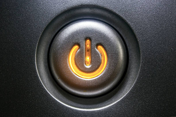 Extreme close-up of a black standby button glowing orange Standby button with orange light. turning on or off stock pictures, royalty-free photos & images