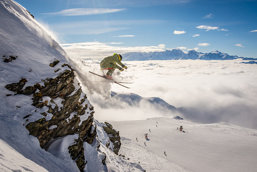 A male skier jumping off a rock, Verbier in the Swiss alps.