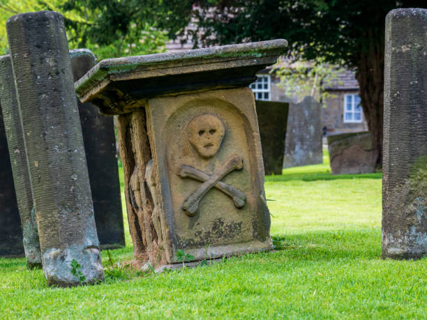 Eyam village church grave yard skull and cross bones carving on the grave stone from the bubonic plague era Eyam village church grave yard skull and cross bones carving on the grave stone from the bubonic plague era bubonic plague photos stock pictures, royalty-free photos & images