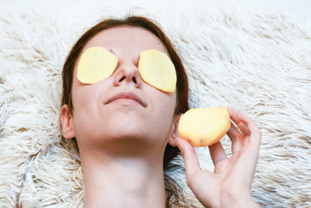 Eye treatement Young, redhead model using potato slices to relieve dark circles dark circles  potato stock pictures, royalty-free photos & images