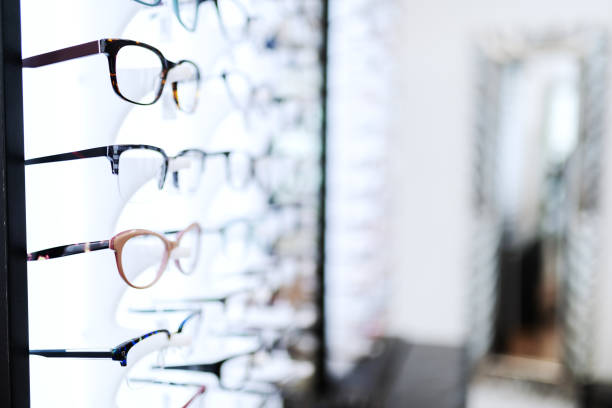 brillen in linie auf regal an optiker sortiert. - brille stock-fotos und bilder