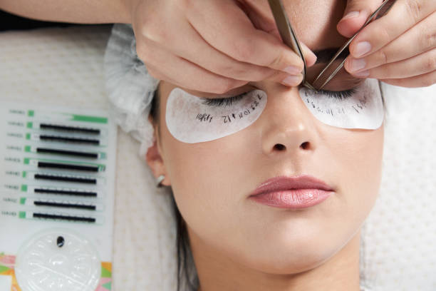 Eyelash extension procedure close up. Beautiful Woman with long lashes in a beauty salon stock photo