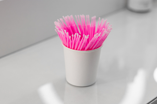Eyelash microbrush applicators. Pink microbrushes in a glass. Consumables. Microbrushes are used in the beauty industry and dentistry