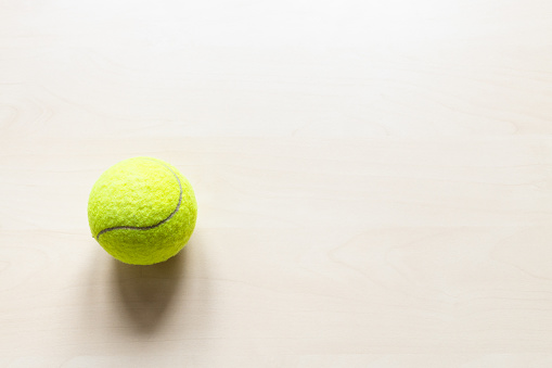 top view of tennis ball on light brown wooden board with copyspace