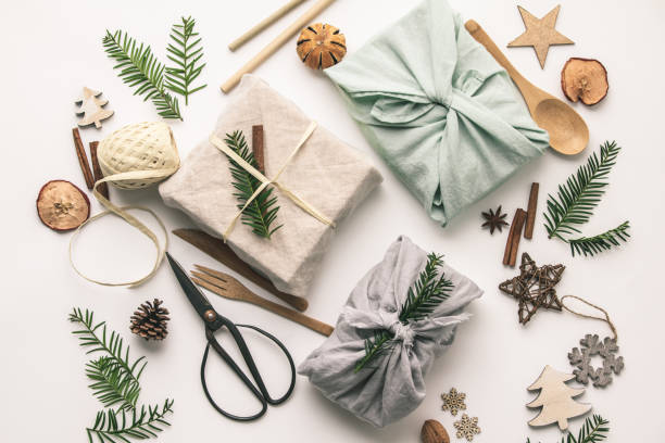 Fabric wrapped gifts and wooden Christmas decorations Fabric wrapped gifts and wooden Christmas decorations, reusable sustainable recycled textile gift wrapping alternative zero waste concept, flat lay, top view zero waste photos stock pictures, royalty-free photos & images