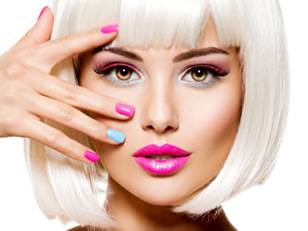 Face of a beautiful woman with pink eye make-up and multicolor nails. stock photo