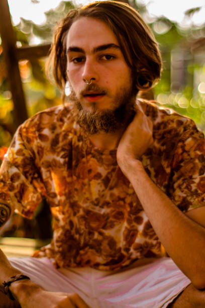 Retrato do rosto de um homem jovem, com barba e cabelo castanho, brinco piercing e exóticas nariz captou ao entardecer