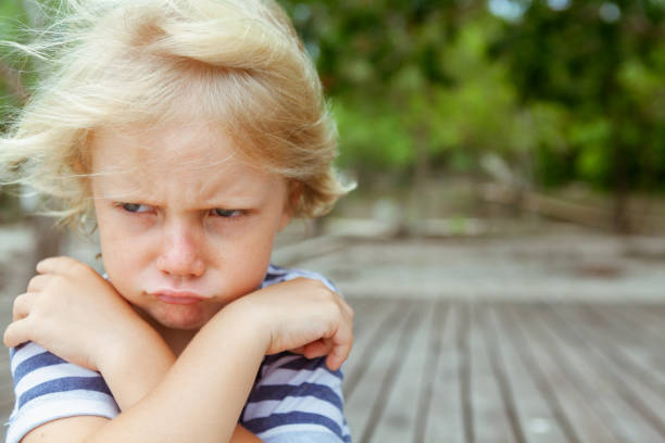 Face portrait of annoyed, unhappy caucasian kid with crossed arms stock photo