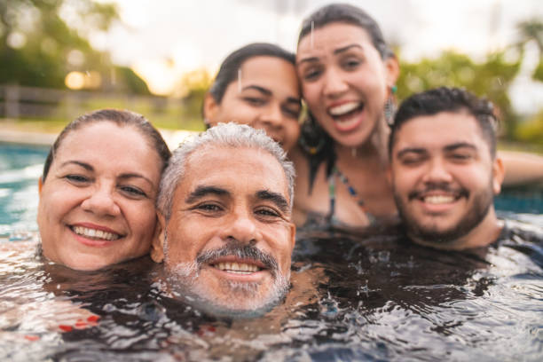 gezichten-familie genieten in het zwembad - rain woman sun stockfoto's en -beelden