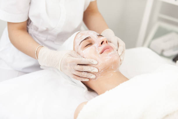 Facial skin care procedures. Beautician makes massage procedure with beauty woman's face in cosmetic clinic stock photo