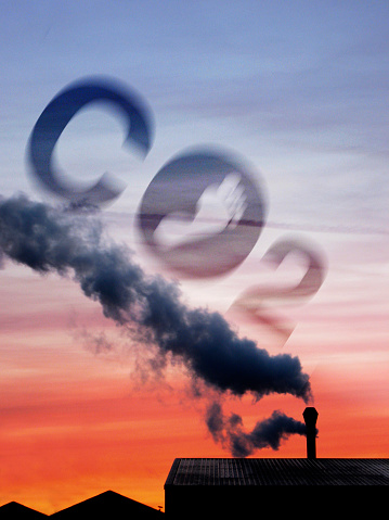 Factory chimney releasing steam at dusk and global warming concept increasing carbon dioxide emissions into the atmosphere