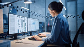 istock Factory Office: Portrait of Beautiful and Confident Female Industrial Engineer Working on Computer, on Screen Industrial Electronics Design Software. High Tech Facility with CNC Machinery 1294339697