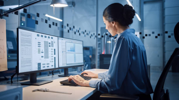 공장 사무실: 스크린 산업용 전자 설계 소프트웨어에서 컴퓨터 작업을 하는 아름답고 자신감 있는 여성 산업 엔지니어의 초상화. cnc 기계가 있는 첨단 시설 - 엔지니어 뉴스 사진 이미지
