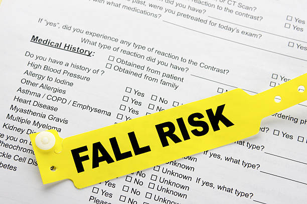 Fall Risk With Hospital  Paperwork A yellow fall risk patient bracelet on top of a hospital questionnaire paperwork inpatient stock pictures, royalty-free photos & images
