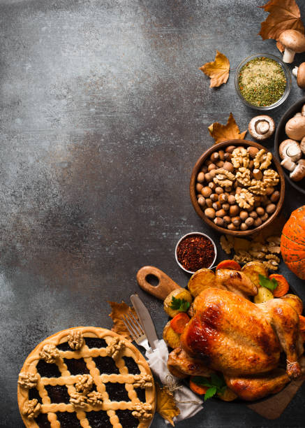 Fall thanksgiving table with roasting chicken or turkey, nuts, pie, pumkins and other food on dark background Fall thanksgiving table with roasting chicken or turkey, nuts, pie, pumkins and other food on dark background, rustic, top view, vertical thanksgiving food stock pictures, royalty-free photos & images
