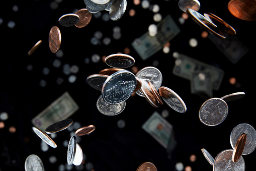 Studio shot of falling coins that appear to defy gravity in the air represent the economy and finance with a nickel in focus