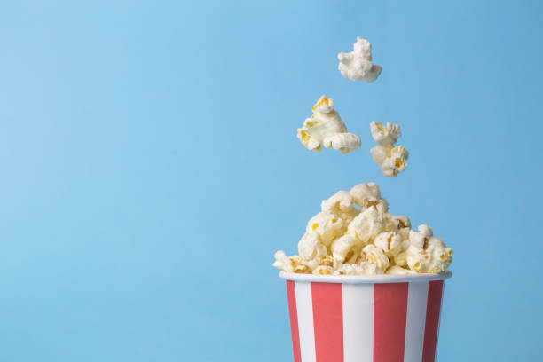 Falling popcorn in box isolated on blue. stock photo