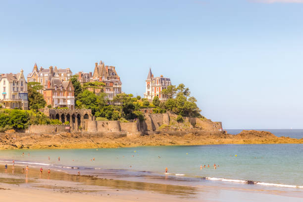 Families at Plage de l'Ecluse enjoy the ocean and sun with views of the expensive properties on the coastline in the distance. stock photo