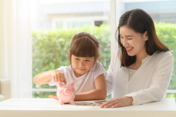 Family 82 mother help daughter in saving money by collecting coils into piggy bank together allowance stock pictures, royalty-free photos & images