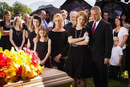 An extended family standing graveside at a funeral.