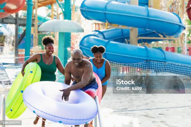 Family at waterpark carry inflatable rings to lazy river