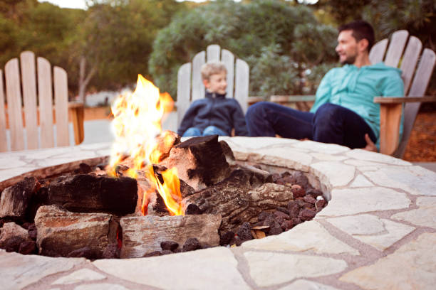 family by firepit view of firepit and happy smiling family of two, father and son, enjoying time together in the background fire pit stock pictures, royalty-free photos & images