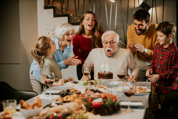 Family celebrating grandfather birthday with cake and candles at home stock photo