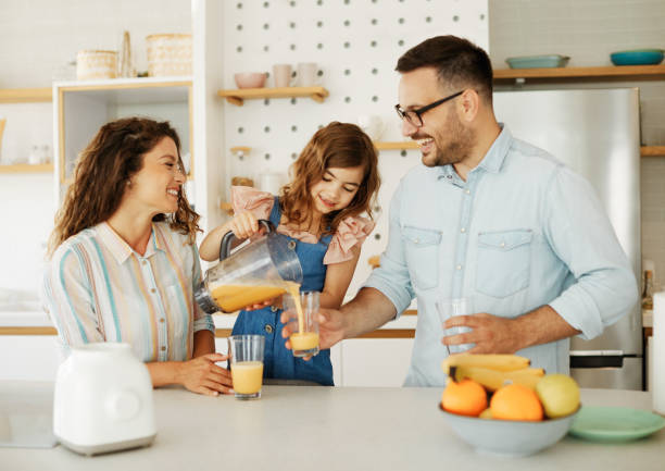 family child kitchen food daughter mother father orange juice healthy preparing drink  breakfast  together stock photo