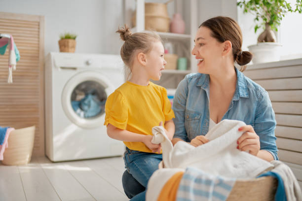family doing laundry Beautiful young woman and child girl little helper are having fun and smiling while doing laundry at home. laundry photos stock pictures, royalty-free photos & images