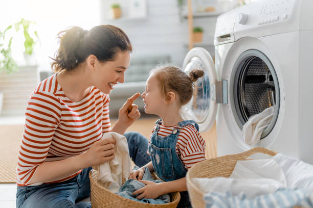 family doing laundry Beautiful young woman and child girl little helper are having fun and smiling while doing laundry at home. washing stock pictures, royalty-free photos & images