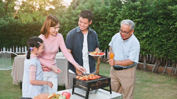Family enjoying a barbecue party celebration in the backyard together stock photo