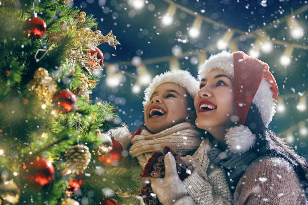 familie genieten van kerstmis - vrouw kerstboom versieren stockfoto's en -beelden