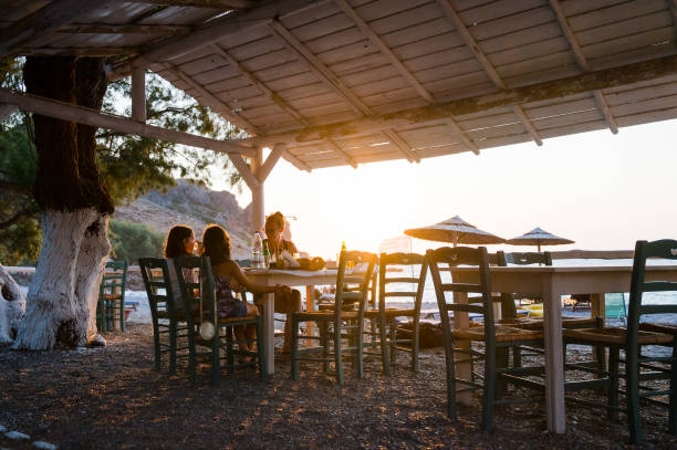 Family enjoying dinner in a restaurant on the beach at sunset. stock photo