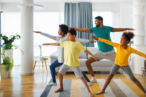 Family exercising at home Closeup front view of a young african american family with son and daughter exercising at home during coronavirus quarantine. They are practicing some yoga moves. relaxation exercise stock pictures, royalty-free photos & images