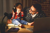 family father and son baby listening to music with headphones in the dark night
