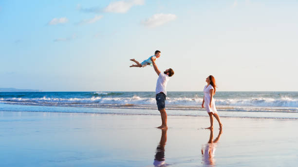 Family - father, mother, baby walk on sunset beach stock photo