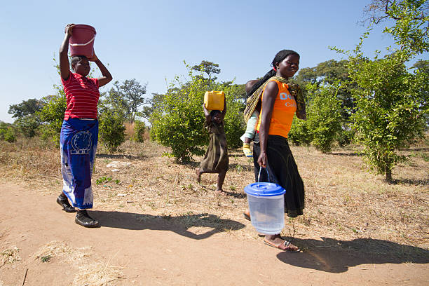Family fetching water with buckets in rural Southern Africa. stock photo