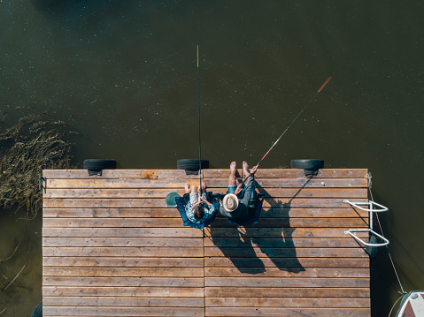 Family spending time together, Father and son fishing on jetty by the lake. Directly above.