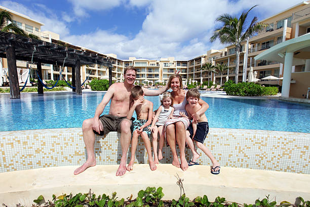 Family Fun on Vacation Family enjoying fun vacation at tropical resort infinity pool. (Father holding up two fingers behind Mother's head, embarrassing son) embarrassment photos stock pictures, royalty-free photos & images