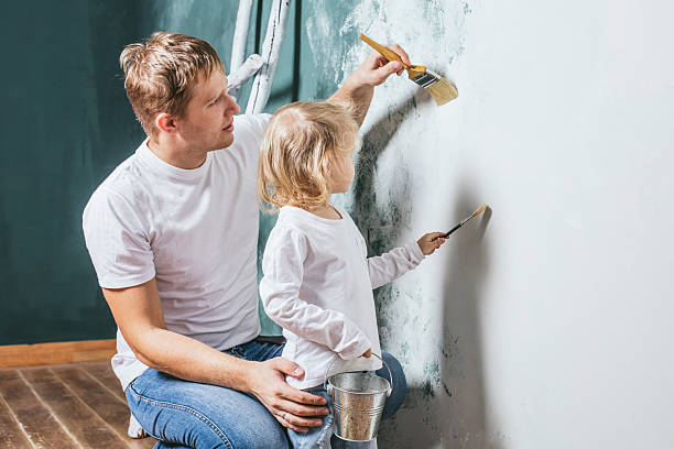 Familia, hija feliz con papá haciendo reparación del hogar, paredes de pintura, - foto de stock