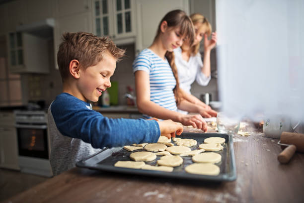 family having fun baking cookies - her happy place is with her team imagens e fotografias de stock
