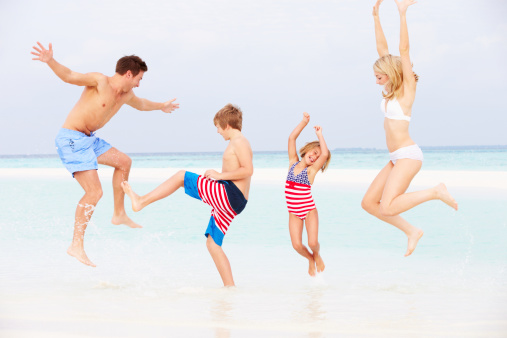 Family Having Fun Playing In Sea On Beach Holiday