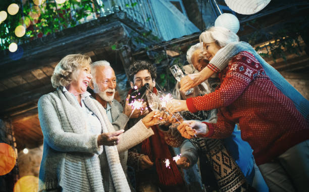 Family having New year's party in a backyard. Closeup of multi generation family having  New year's party in a backyard. They are toasting with champagne and lighting up some sparklers. 60 69 years photos stock pictures, royalty-free photos & images